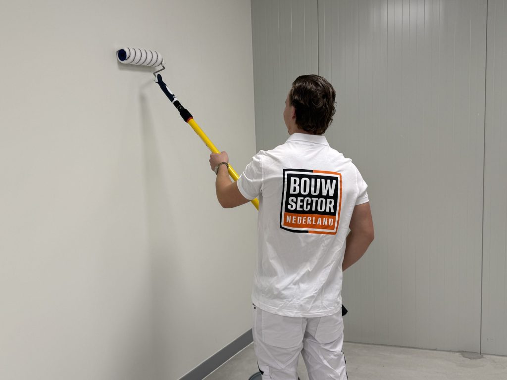 Schilder van Bouwsector Nederland zet met een verlengsteel een witte wand in de verf